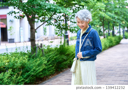A senior woman smiling on a tree-lined street A senior woman smiling on a tree-lined street 139412232