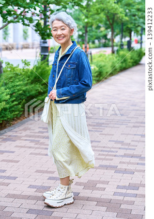 Full body shot of a senior woman posing on a tree-lined street Full body shot of a senior woman posing on a tree-lined street 139412233