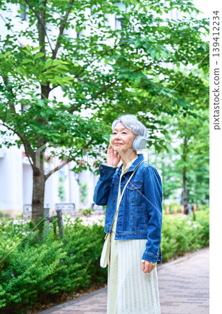 一位戴著耳機的老婦人抬頭望向天空。 139412234