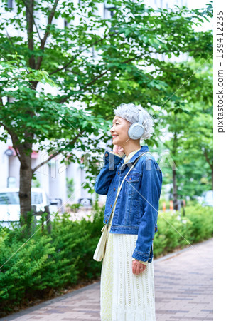A senior woman wearing headphones and smiling. A senior woman wearing headphones and smiling. 139412235