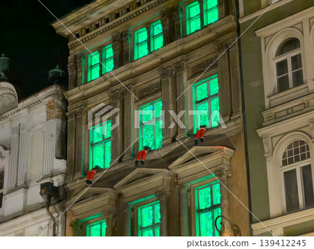 Ornate historic building showcasing bright green glowing windows and charming festive decorative figures, creating a mysterious holiday night display Ornate historic building showcasing bright green glowing windows and charming festive decorative figures, creating a mysterious holiday night display 139412245