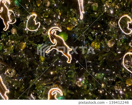 Glowing goat-shaped lights and sparkling ornaments adorn a vibrant Christmas tree, creating a magical festive ambiance for winter holiday celebrations Glowing goat-shaped lights and sparkling ornaments adorn a vibrant Christmas tree, creating a magical festive ambiance for winter holiday celebrations 139412246