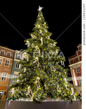 Prominent Christmas tree magnificently illuminated in a city square, adorned with festive lights and unique glowing ram-shaped ornaments, symbolizing holiday cheer Prominent Christmas tree magnificently illuminated in a city square, adorned with festive lights and unique glowing ram-shaped ornaments, symbolizing holiday cheer 139412247
