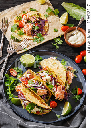 salmon tacos drizzled with sauce on a plate 139412347