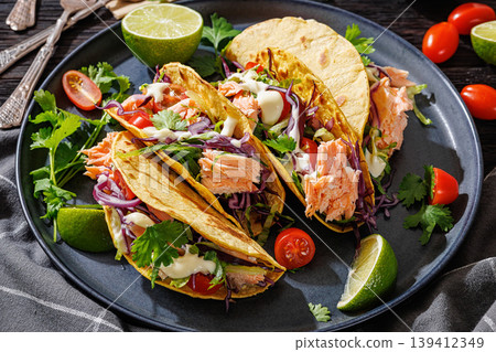 salmon tacos drizzled with sauce on a plate salmon tacos drizzled with sauce on a plate 139412349