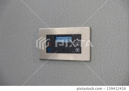 Modern digital thermostat displaying 23.9 degrees and Auto mode on a gray textured wall for smart home climate control system 139412416