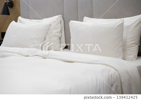 Luxurious white hotel bed prepared with multiple soft pillows and a fresh crisp duvet, promising ultimate comfort and restful relaxation Luxurious white hotel bed prepared with multiple soft pillows and a fresh crisp duvet, promising ultimate comfort and restful relaxation 139412425