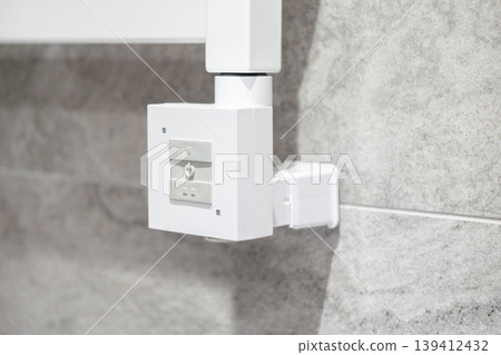 White electric heating controller with buttons mounted on a grey tiled bathroom wall, showcasing modern comfort technology and energy management White electric heating controller with buttons mounted on a grey tiled bathroom wall, showcasing modern comfort technology and energy management 139412432