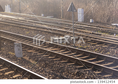 Multiple railway tracks with converging lines on gravel, featuring a signal post and control boxes, symbolizing essential transportation infrastructure and logistics Multiple railway tracks with converging lines on gravel, featuring a signal post and control boxes, symbolizing essential transportation infrastructure and logistics 139412454