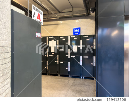 Numbered dark grey luggage lockers offer convenient secure temporary storage for travelers in a busy public transportation terminal, displayed near a TERMINAL A sign Numbered dark grey luggage lockers offer convenient secure temporary storage for travelers in a busy public transportation terminal, displayed near a TERMINAL A sign 139412506