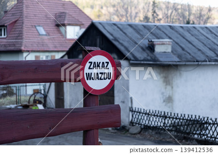 Red and white no entry sign ZAKAZ WJAZDU on a rustic wooden barrier, prohibiting vehicle access to a private residential area, symbolizing restriction and safety Red and white no entry sign ZAKAZ WJAZDU on a rustic wooden barrier, prohibiting vehicle access to a private residential area, symbolizing restriction and safety 139412536