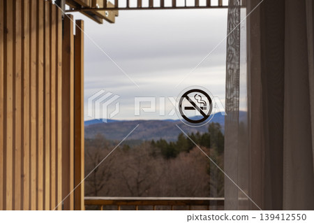 No smoking prohibition sign clearly displayed on a hotel balcony's glass door, overlooking a picturesque autumn mountain landscape, promoting health and safety No smoking prohibition sign clearly displayed on a hotel balcony's glass door, overlooking a picturesque autumn mountain landscape, promoting health and safety 139412550