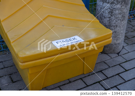 Robust yellow grit bin prominently labeled SAND FOR WINTER ACTION, a crucial municipal asset for public road safety and proactive winter weather preparedness 139412570