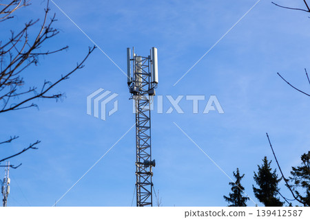 Modern cellular communication tower stands tall with multiple antennas against a bright clear blue sky, symbolizing essential global network infrastructure technology Modern cellular communication tower stands tall with multiple antennas against a bright clear blue sky, symbolizing essential global network infrastructure technology 139412587