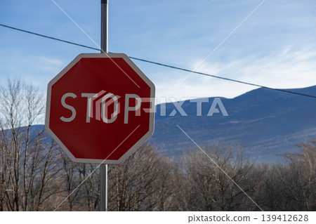 Vibrant red octagonal STOP sign prominently displayed on a pole against a clear blue sky, emphasizing vital traffic regulation and promoting essential road safety for drivers Vibrant red octagonal STOP sign prominently displayed on a pole against a clear blue sky, emphasizing vital traffic regulation and promoting essential road safety for drivers 139412628