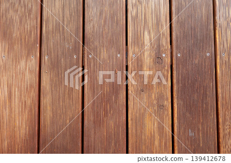 Close-up view of brown wooden planks with textured ridges and visible screws, creating a natural rustic background for outdoor decking or interior design Close-up view of brown wooden planks with textured ridges and visible screws, creating a natural rustic background for outdoor decking or interior design 139412678