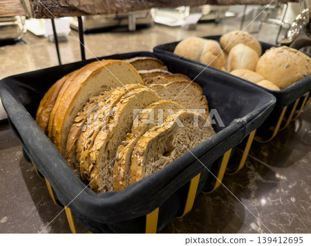 Freshly baked sliced bread and rolls displayed in baskets, offering a delicious variety for breakfast or a catered event, emphasizing healthy eating Freshly baked sliced bread and rolls displayed in baskets, offering a delicious variety for breakfast or a catered event, emphasizing healthy eating 139412695
