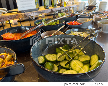 Fresh vegetable buffet with diverse healthy salad ingredients displayed, promoting nutritious dining options and self-service in a modern restaurant setting 139412720