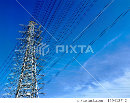 高壓輸電線路和輸電塔高聳入雲,映襯著蔚藍的天空。 高壓輸電線路和輸電塔高聳入雲,映襯著蔚藍的天空。 139412742