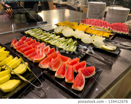 Vibrant breakfast buffet display offers a wide assortment of freshly sliced fruit, including grapefruit, kiwi, pineapple, melon, and watermelon, promoting healthy lifestyle choices Vibrant breakfast buffet display offers a wide assortment of freshly sliced fruit, including grapefruit, kiwi, pineapple, melon, and watermelon, promoting healthy lifestyle choices 139412876