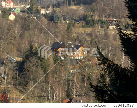 Remote mountain village features houses nestled among bare trees, conveying a peaceful winter atmosphere for rural living and natural retreat Remote mountain village features houses nestled among bare trees, conveying a peaceful winter atmosphere for rural living and natural retreat 139412888