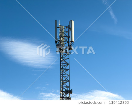 Contemporary cellular telecommunication tower, featuring multiple antennas, stands against a bright blue sky, symbolizing seamless global network connectivity and digital infrastructure 139412893