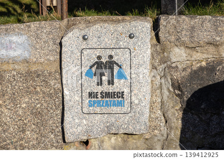 Granite sign with stick figures holding trash bags and Do not litter I clean message, promoting environmental care and public space cleanliness 139412925