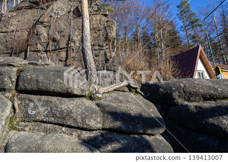 Rugged outdoor climbing wall built into natural rock formations with visible ropes and star holds, highlighting adventure sports, recreation, and forest tourism Rugged outdoor climbing wall built into natural rock formations with visible ropes and star holds, highlighting adventure sports, recreation, and forest tourism 139413007