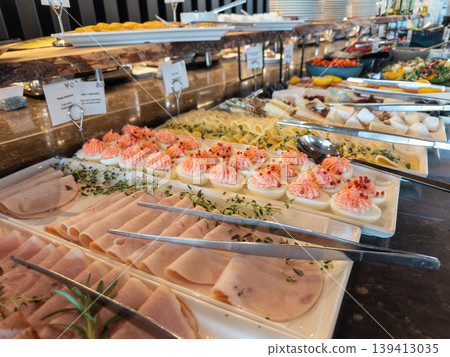Abundant hotel breakfast buffet featuring a variety of cold cuts, deviled eggs, and gourmet cheese selections, ready for guest enjoyment Abundant hotel breakfast buffet featuring a variety of cold cuts, deviled eggs, and gourmet cheese selections, ready for guest enjoyment 139413035
