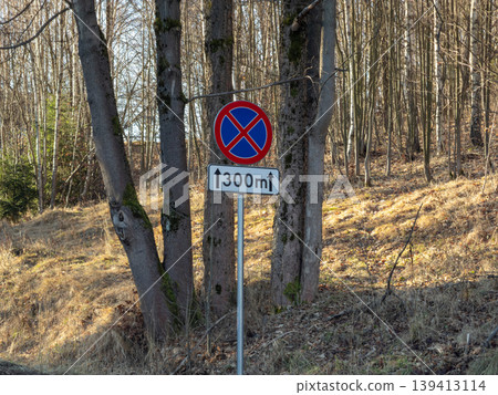No parking traffic sign with a 300 meter distance plate installed on a rural forest roadside, indicating strict vehicle standing and stopping prohibition for drivers along this stretch of the road No parking traffic sign with a 300 meter distance plate installed on a rural forest roadside, indicating strict vehicle standing and stopping prohibition for drivers along this stretch of the road 139413114