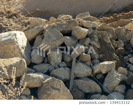 Large rugged rocks piled at a construction site represent natural materials used for essential structural foundation work, professional landscaping development, and heavy industrial earthwork projects Large rugged rocks piled at a construction site represent natural materials used for essential structural foundation work, professional landscaping development, and heavy industrial earthwork projects 139413132