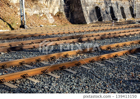 Parallel railway tracks extend through a scenic mountain passage with rocky embankments, symbolizing travel, journey, industrial connectivity, and infrastructure development within a natural landscape Parallel railway tracks extend through a scenic mountain passage with rocky embankments, symbolizing travel, journey, industrial connectivity, and infrastructure development within a natural landscape 139413150