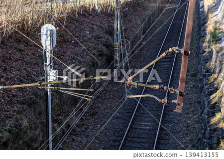 A high view of a railway catenary system featuring overhead wires and metal support structures along the track, representing modern rail infrastructure, logistics connectivity, and efficient transport A high view of a railway catenary system featuring overhead wires and metal support structures along the track, representing modern rail infrastructure, logistics connectivity, and efficient transport 139413155