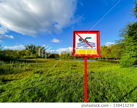 Sign on Bank of the lake is forbidden to swim on a summer day. Pointer that you can not swim here dirty water 139413239