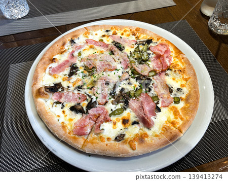 Amateur shot of pizza on restaurant table. Slightly uneven crust, melted cheese pooling. Real friendship meal without filters. Authentic evening, unpolished and warm Amateur shot of pizza on restaurant table. Slightly uneven crust, melted cheese pooling. Real friendship meal without filters. Authentic evening, unpolished and warm 139413274