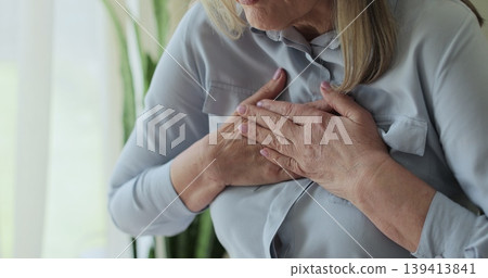 Close up old woman, chest inflammation and cardiovascular emergency in lounge, panic attack and physical symptoms. Close up old woman, chest inflammation and cardiovascular emergency in lounge, panic attack and physical symptoms. 139413841