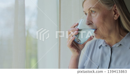 Close up healthy old woman drinking water for healthcare or natural vitamins in a house. Senior person refreshing with liquid for energy or hydration. Close up healthy old woman drinking water for healthcare or natural vitamins in a house. Senior person refreshing with liquid for energy or hydration. 139413863