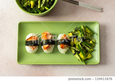 Food is arranged on a green plate with salad made of nori, cucumbers, and avocado alongside nagiri sushi topped with red fish, suitable for breakfast or lunch Food is arranged on a green plate with salad made of nori, cucumbers, and avocado alongside nagiri sushi topped with red fish, suitable for breakfast or lunch 139413876