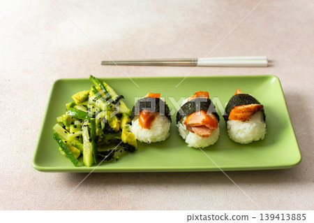 Food is arranged on a green plate with salad made of nori, cucumbers, and avocado alongside nagiri sushi topped with red fish, suitable for breakfast or lunch Food is arranged on a green plate with salad made of nori, cucumbers, and avocado alongside nagiri sushi topped with red fish, suitable for breakfast or lunch 139413885