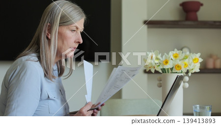 Senior woman working with laptop while checking some documents at home. Remote work concept. 139413893