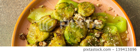 Baked Brussels sprouts are combined with zucchini slices and walnuts. The dish is served on a plate, ready for breakfast or lunch at home, banner Baked Brussels sprouts are combined with zucchini slices and walnuts. The dish is served on a plate, ready for breakfast or lunch at home, banner 139413896