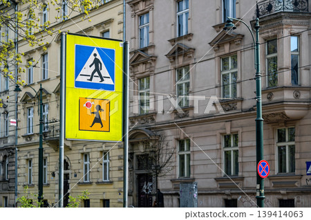 Traffic signs show pedestrian and child walking on city street with buildings in background 139414063