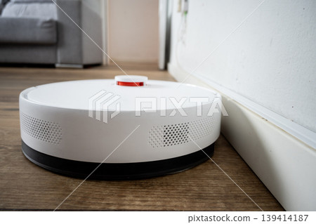 Robot vacuum cleaner cleaning wooden floor in modern living room 139414187