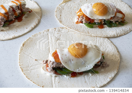 Tortilla wraps with mozzarella, vegetables, tuna, and fried egg on white background Tortilla wraps with mozzarella, vegetables, tuna, and fried egg on white background 139414834
