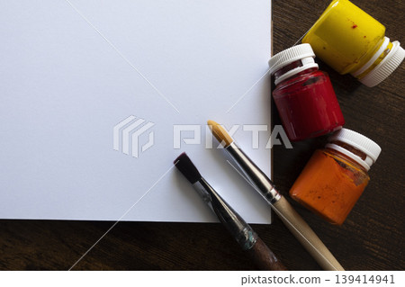 Flat lay of sketchbook with paint brushes and paint tubes on wooden table with copy space, top view Flat lay of sketchbook with paint brushes and paint tubes on wooden table with copy space, top view 139414941