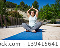 Woman Practicing Outdoor Yoga Meditation On Mat In Sunny Park For Wellness And Fitness 139415641