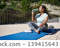 Woman Drinking Water on Yoga Mat After Outdoor Workout and Stretching 139415643