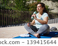 Woman Resting After Outdoor Yoga Workout With Water Bottle On Mat 139415644