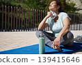 Woman Resting on Yoga Mat After Outdoor Workout Wiping Sweat With Towel 139415646
