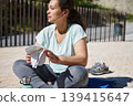 Woman Resting After Outdoor Workout With Towel and Water Bottle 139415647